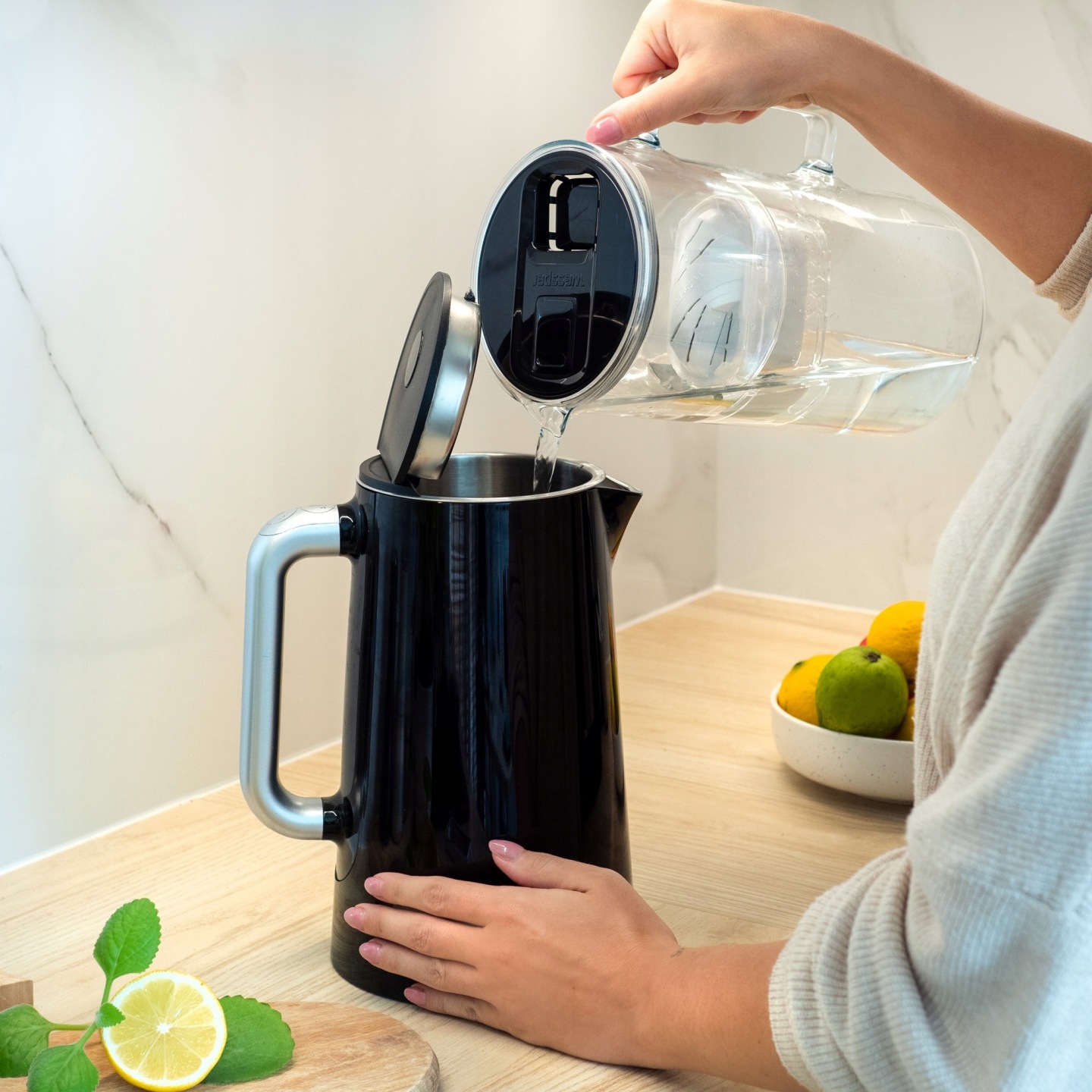 Kobieta nalewa wodę z&nbsp;dzbanka filtrującego Wessper D2 do czajnika